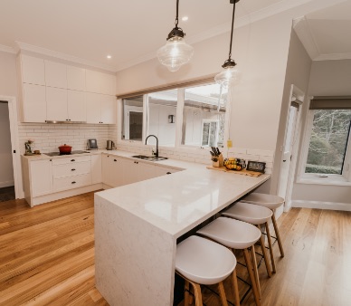 A modern white, country style kitchen with a breakfast bar and hardwood floors