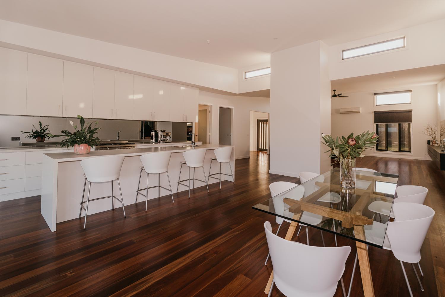 A large kitchen with sleek white cabinetry bordering a spacious dinning room